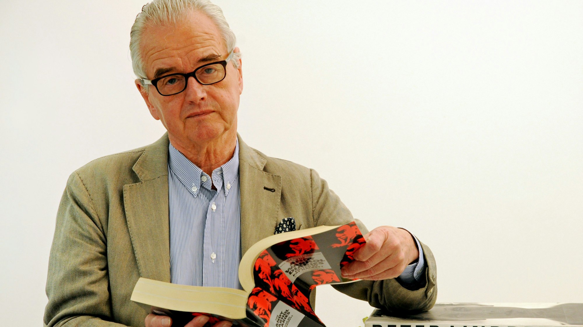 Der Galerist Hans Mayer blättert in seiner Galerie in Düsseldorf in einem Katalog.