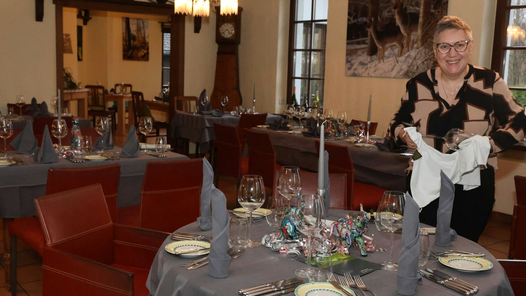 Marlies Allmann steht vor einem Tisch, den sie gerade am Eindecken ist.