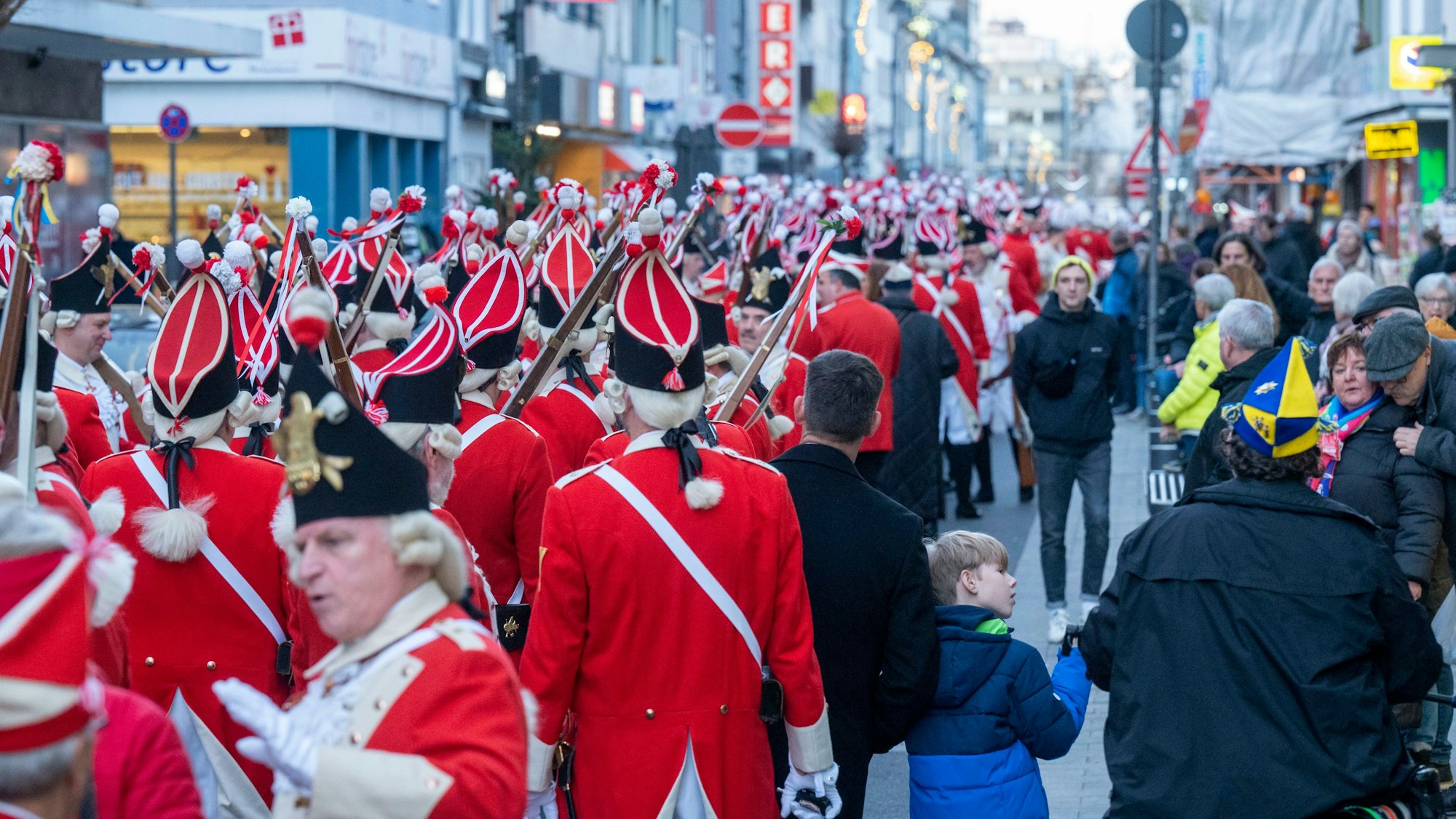 Viele verkleidete Menschen laufen hintereinander in einem Karnevalszug.