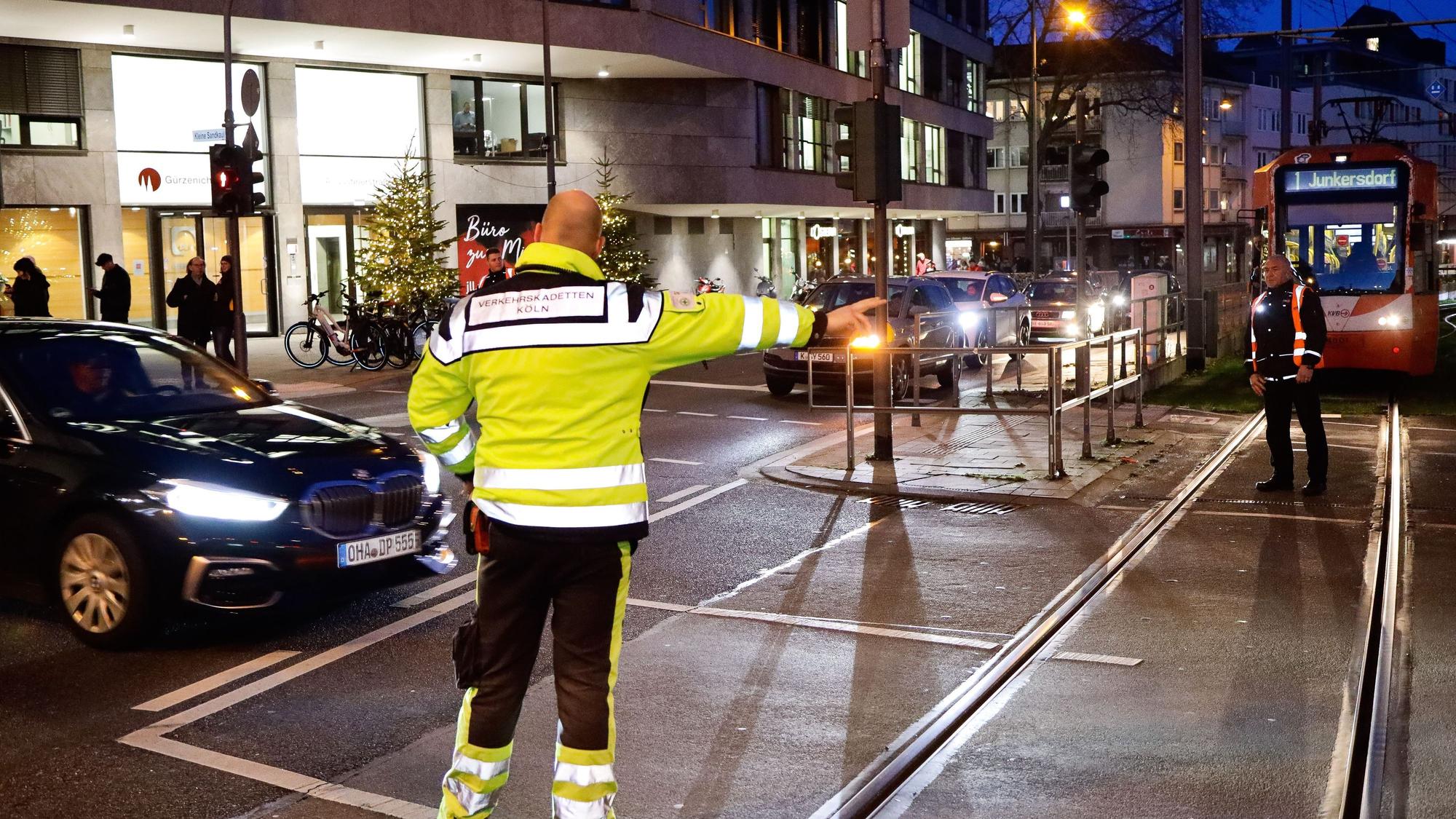 Menschen in Warnwesten regeln den Kölner Verkehr, der wegen des Zugs von Karnevalisten gestört ist.