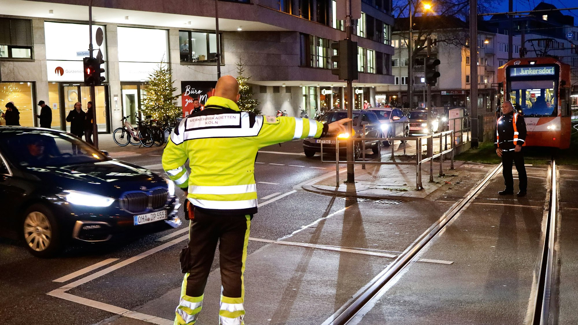 Menschen in Warnwesten regeln den Kölner Verkehr, der wegen des Zugs von Karnevalisten gestört ist.