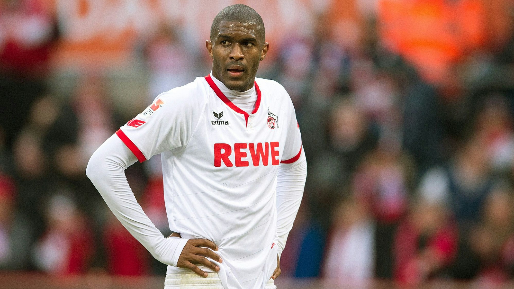 Fußballspieler Anthony Modeste steht im FC-Trikot auf dem Rasen und stützt die Hande in die Hüfte.