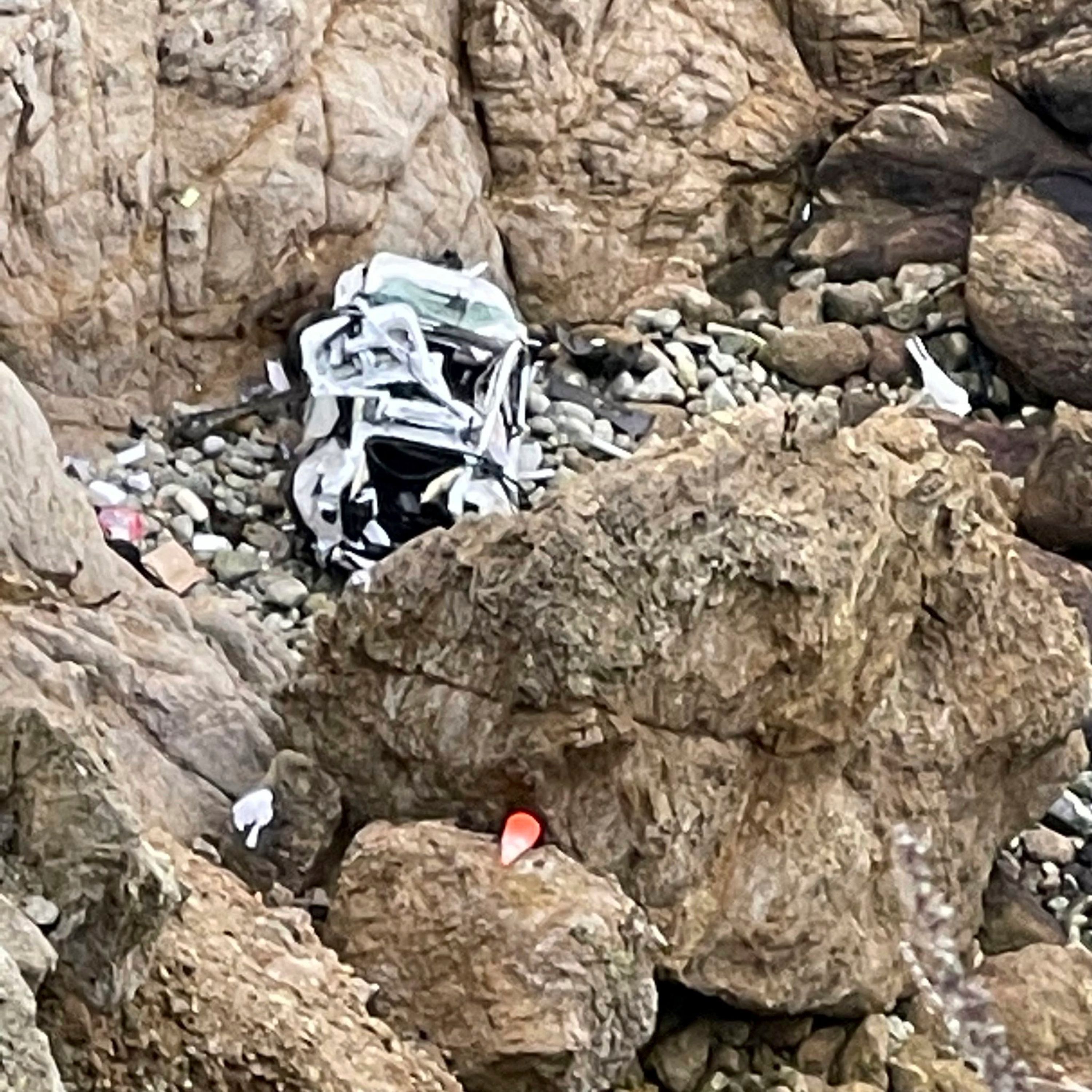 Ein völlig zerstörter weißer Tesla liegt in der Bucht „Devils Slide“ in Kalifornien. Ein Helikopter muss die Insassen retten.