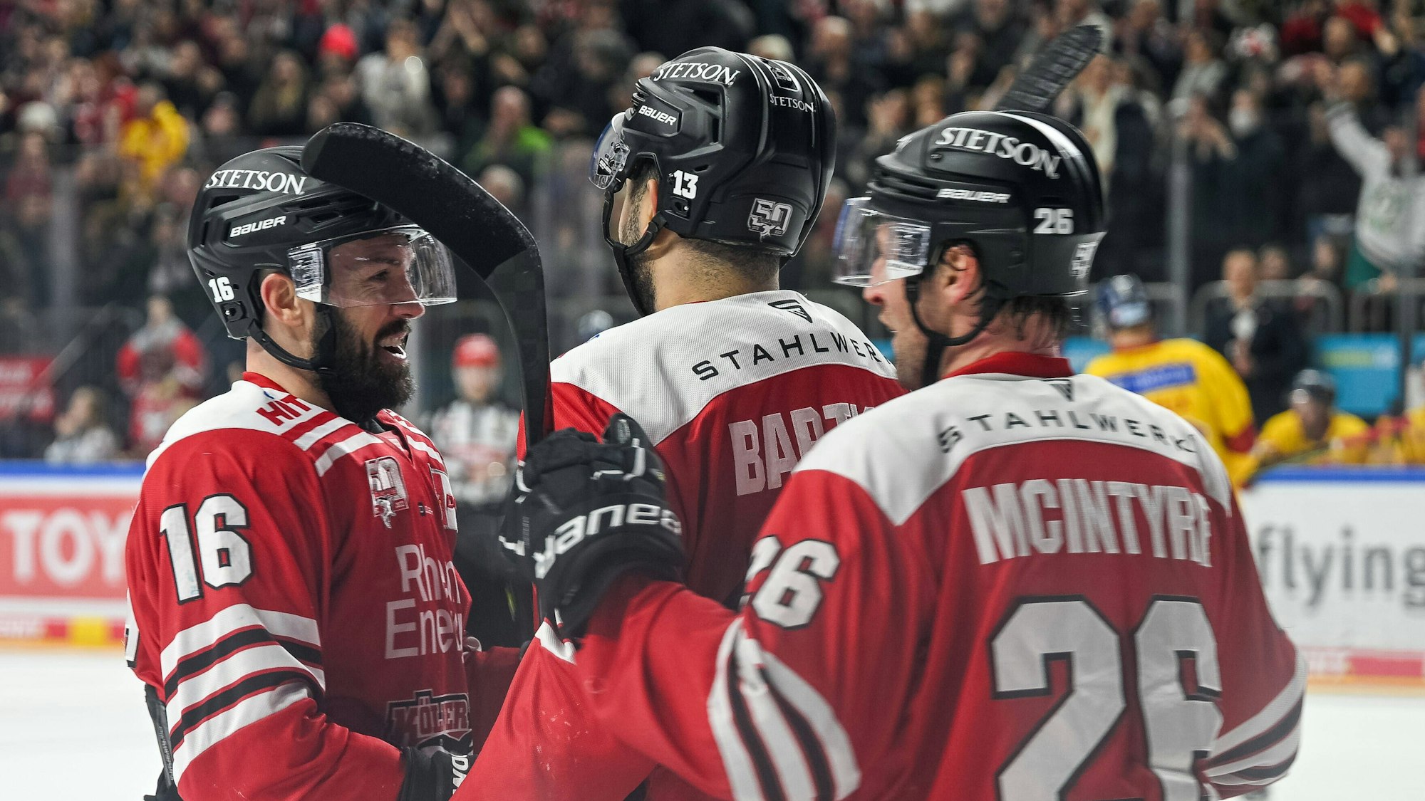 Spieler der Kölner Haie jubeln gemeinsam uaf dem Eis.