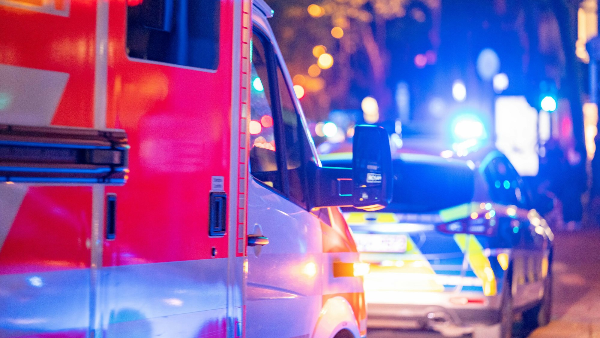 Ein Rettungswagen und ein Wagen der Polizei stehen nachts hintereinander am Straßenrand.