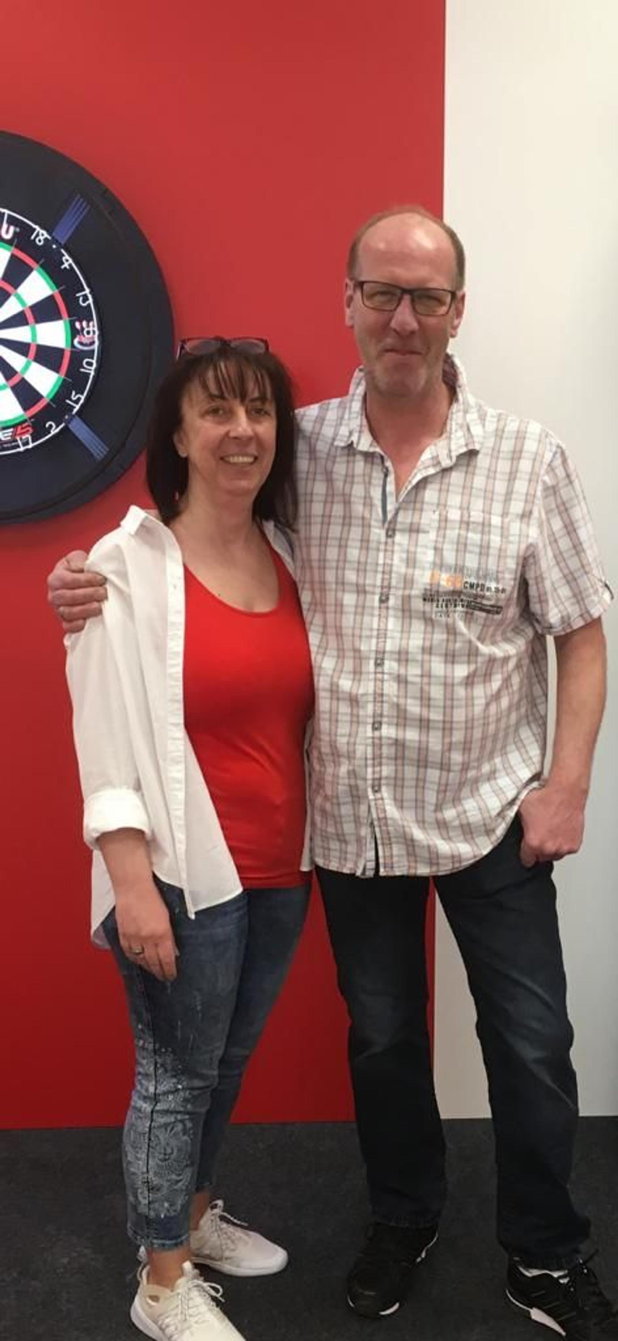 Michael Klein, Inhaber des Cologne Dartshops in Köln-Nippes steht auf dem Foto neben seiner Frau.