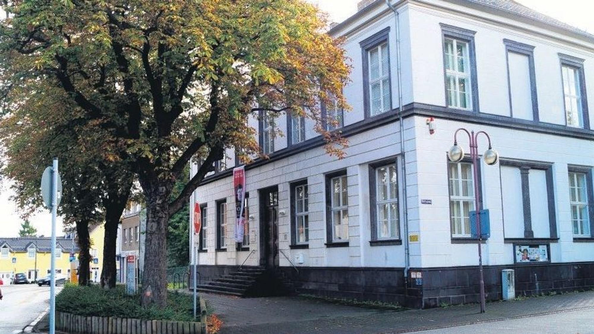 Das Haus für Kunst und Geschichte, ein weißes Gebäude an einer Straßenecke. Davor steht ein herbstlich belaubter Baum und einige Schilder.