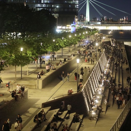 04.06.2022, Köln: Eine warme Nacht in Deutz.Menschen genießen auf den Treppen des Rheinboulevard den Frühsommer.