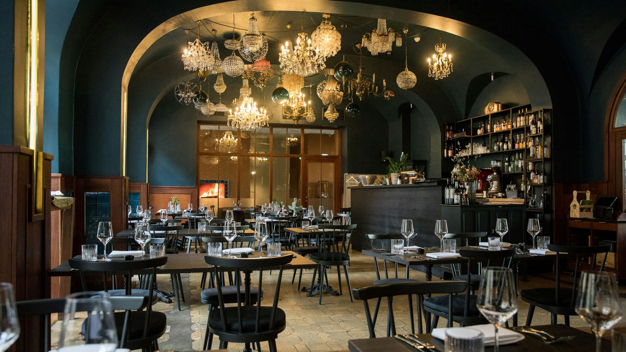 Das Restaurant Augustin in Köln. Gedeckte Tische, Stühle und viele Kronleuchter an der Decke.