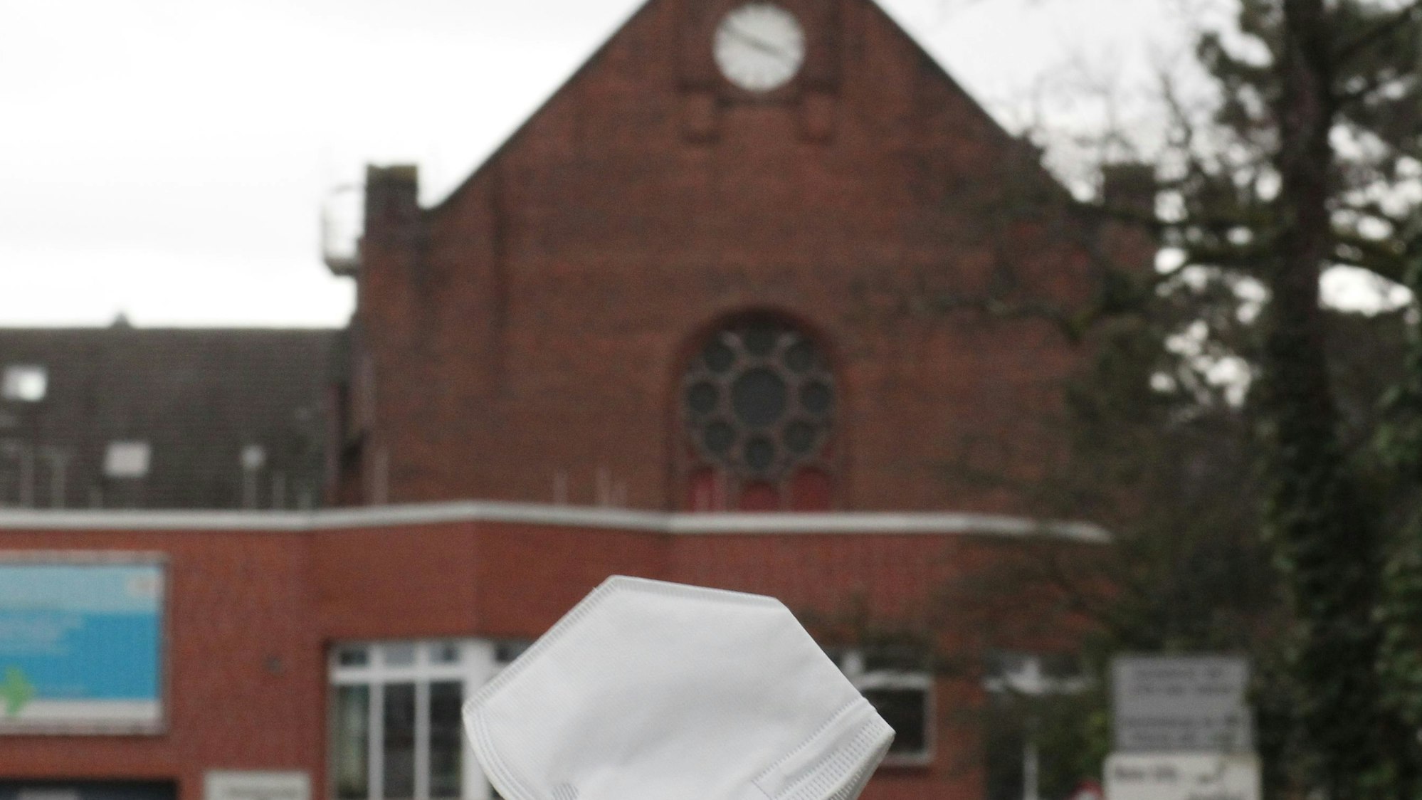 Der Eingang der Siegburger Gefängnisses, im Hintergrund ein Zellentrakt, im Vordergrund eine FFP2-Maske.