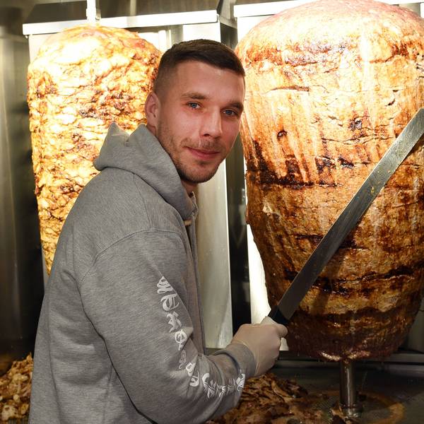 Lukas Podolski steht bei der Eröffnung eines Döner-Ladens an einem Dönerspieß.