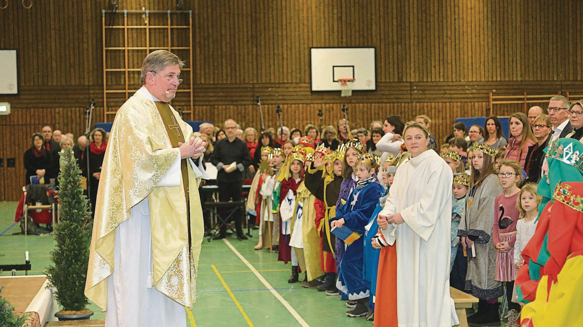 Pastro Harald Fischer steht in einer Kürtener Turnhalle vor Hunderten Menschen.
