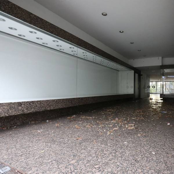 Vor den Eingang eines Geschäftes an der Hauptstraße, dessen Auslagen hinter den Fensterfronten leer sind, hat der Wind Laub geweht.