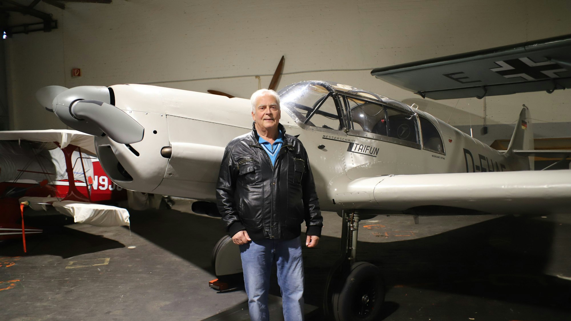 Professor Heinz-Dieter Schneider steht vor einem weißen Flugzeug mit Propeller.