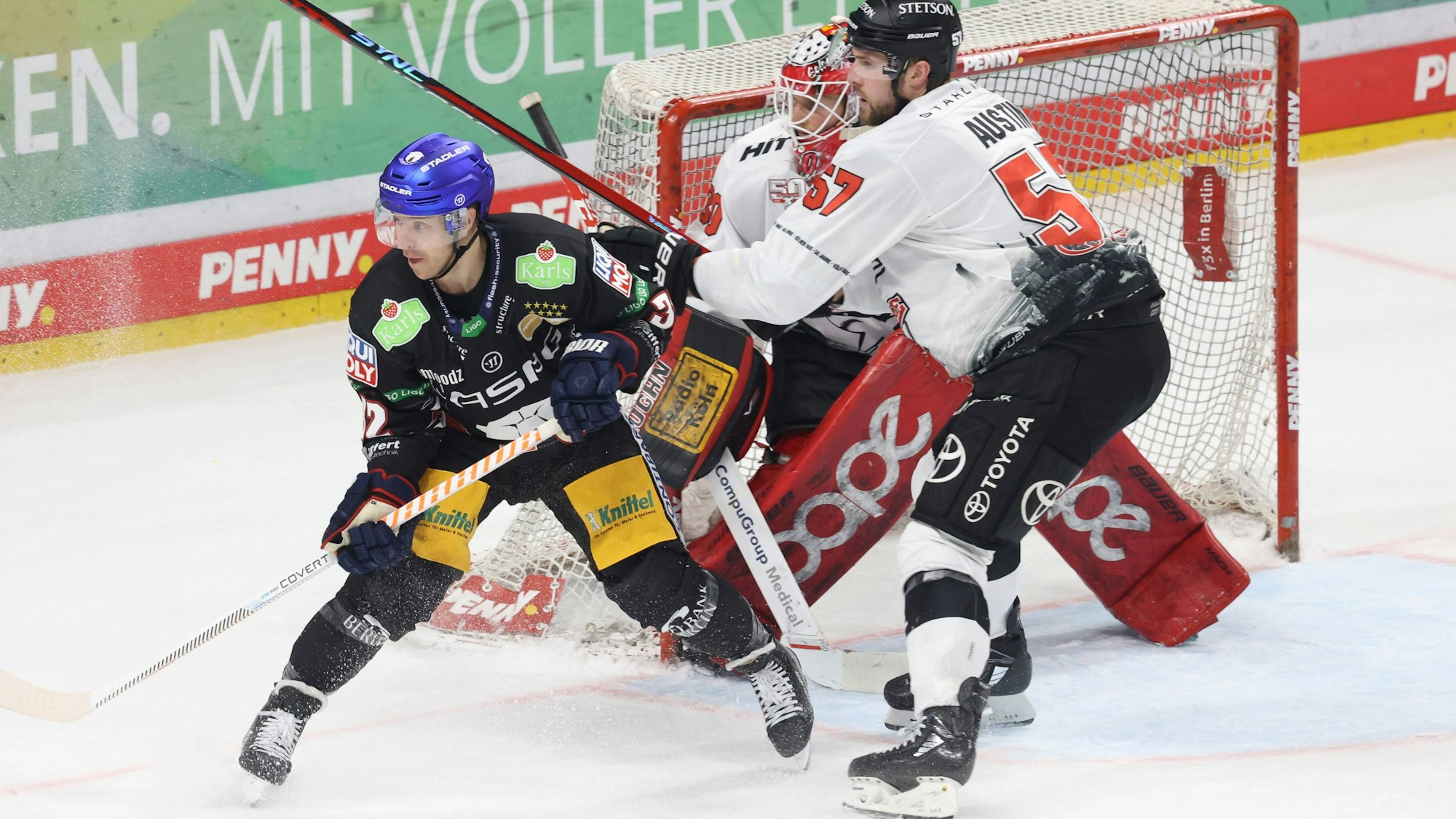 Kevin Clark von den Eisbären Berlin und Kölner Brady Austin in einer Zweikampf-Szene vor dem Kölner Tor.