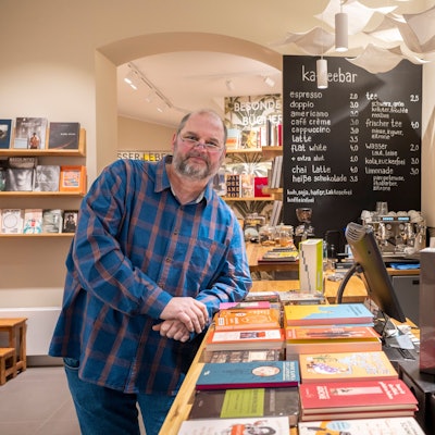Urs Erdle steht in seinem Buchladen, im Hintergrund ist die Kaffeebar zu sehen.