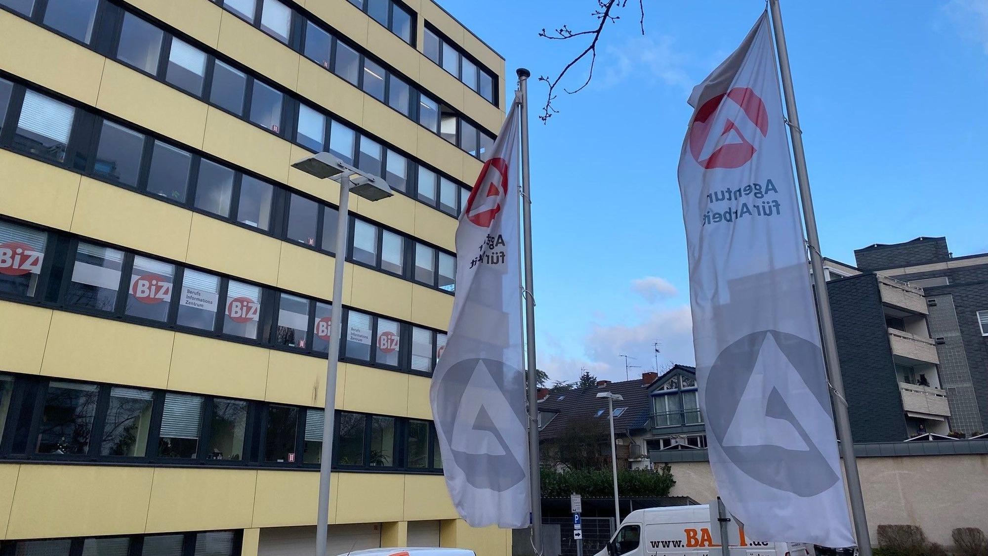 Das Gebäude der Agentur für Arbeit von außen. Vor dem Gebäude wehen zwei Fahnen.