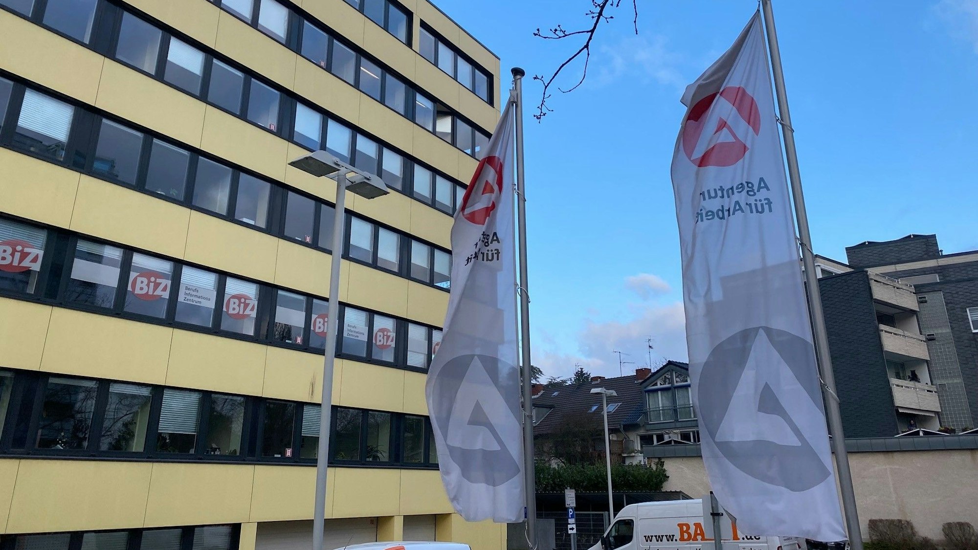 Das Gebäude der Agentur für Arbeit von außen. Vor dem Gebäude wehen zwei Fahnen.