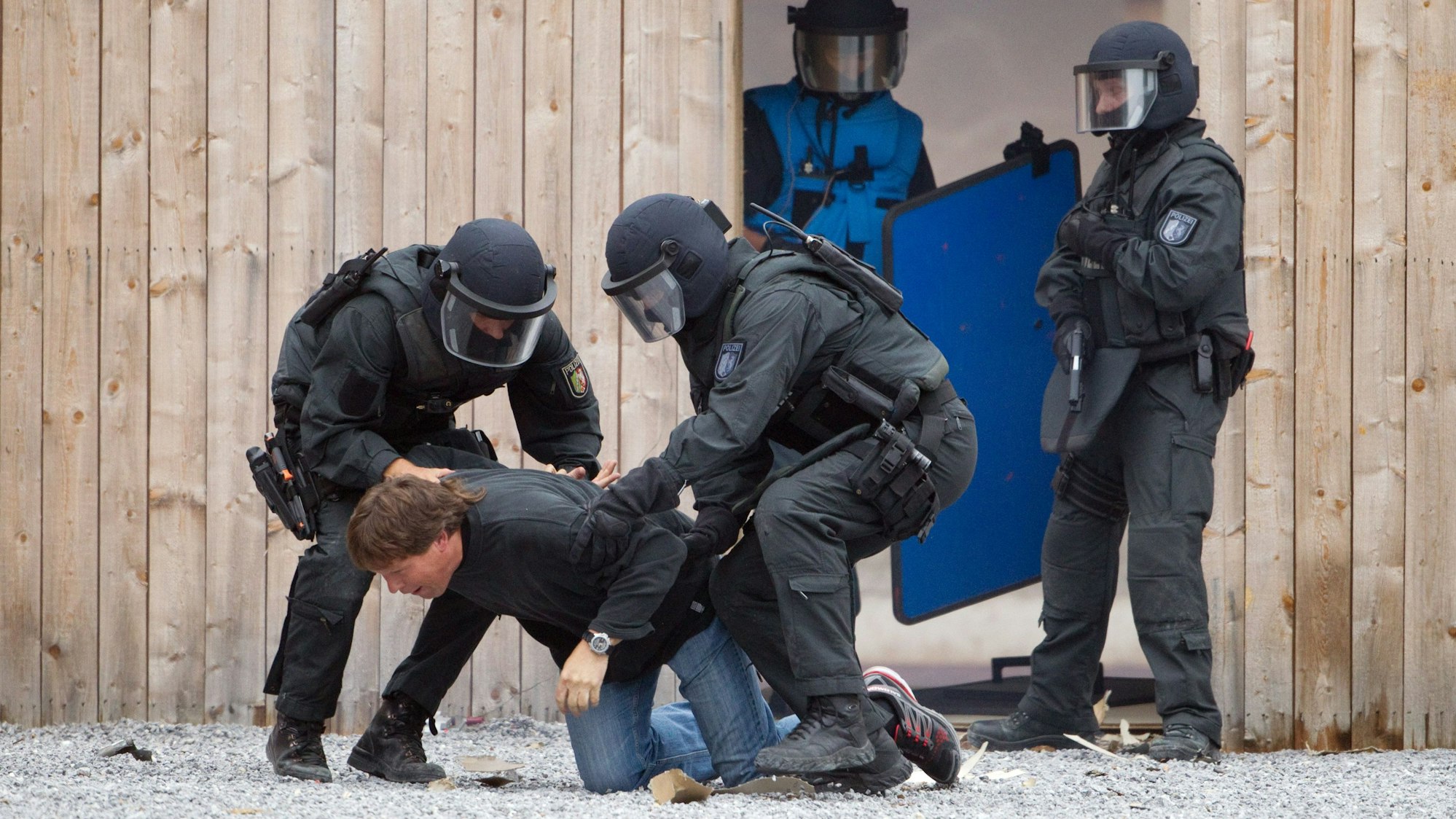 Zu sehen ist, wie schwer bewaffnete Polizisten einen Mann überwältigen. Das Foto entstand bei einer Übung.