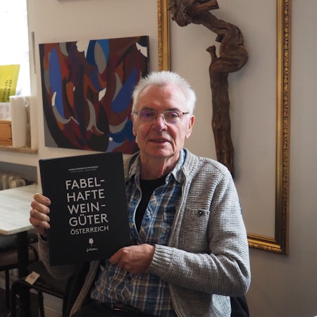 Armin Faber hält das Buch „Fabelhafte Weingüter Österreich“ in der Hand.