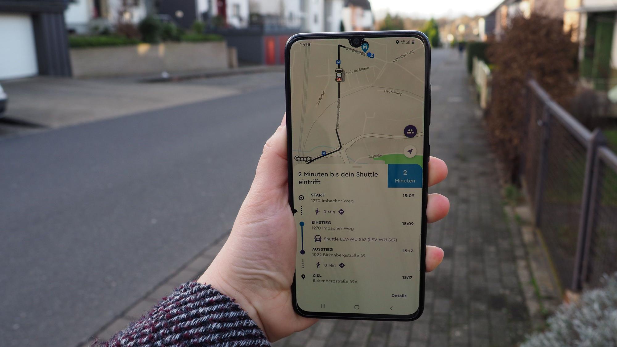 Eine Hand hält ein Smartphone mit der geöffneten „Efi“-App in einer Straße hoch.