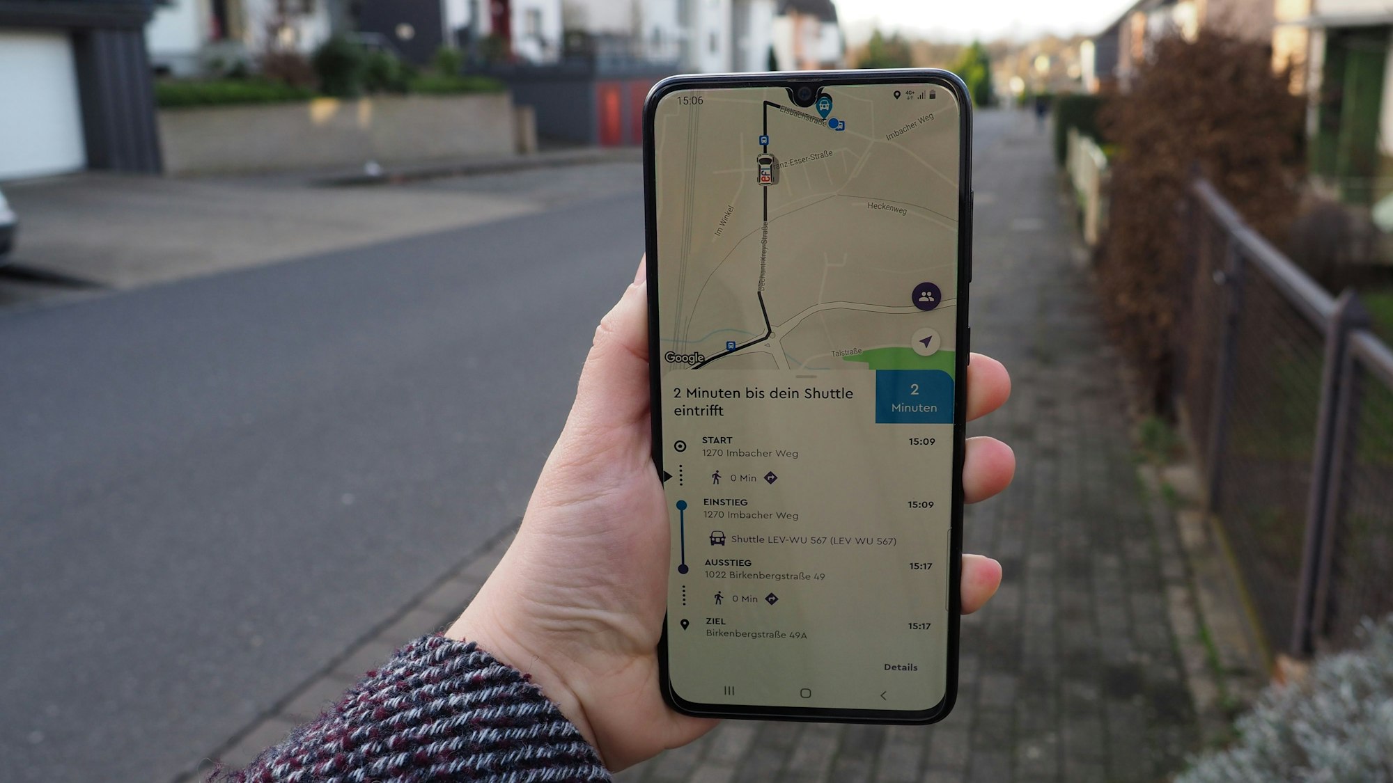 Eine Hand hält ein Smartphone mit der geöffneten „Efi“-App in einer Straße hoch.
