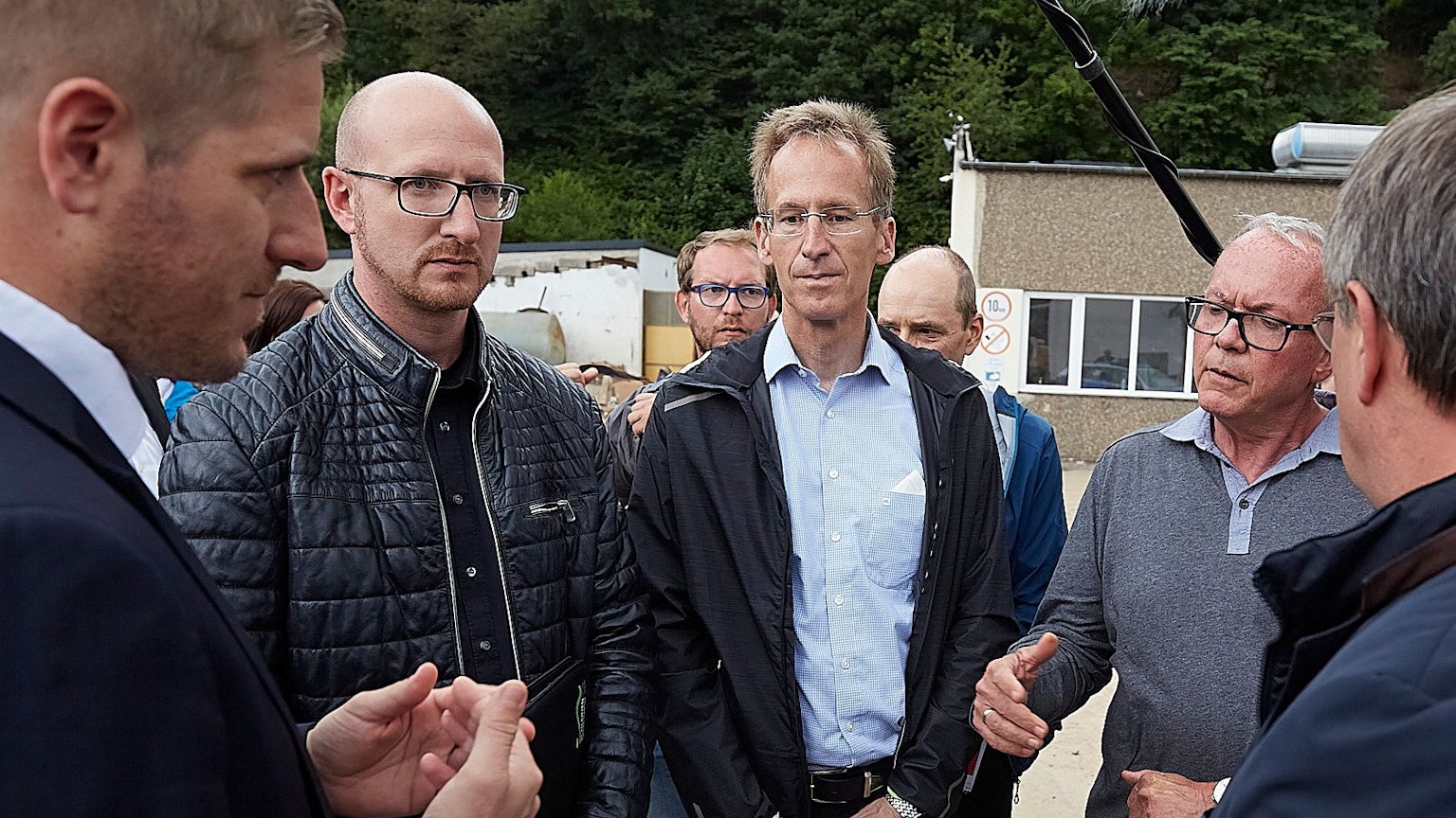Drei Männer stehen mit ernsten Mienen zusammen.