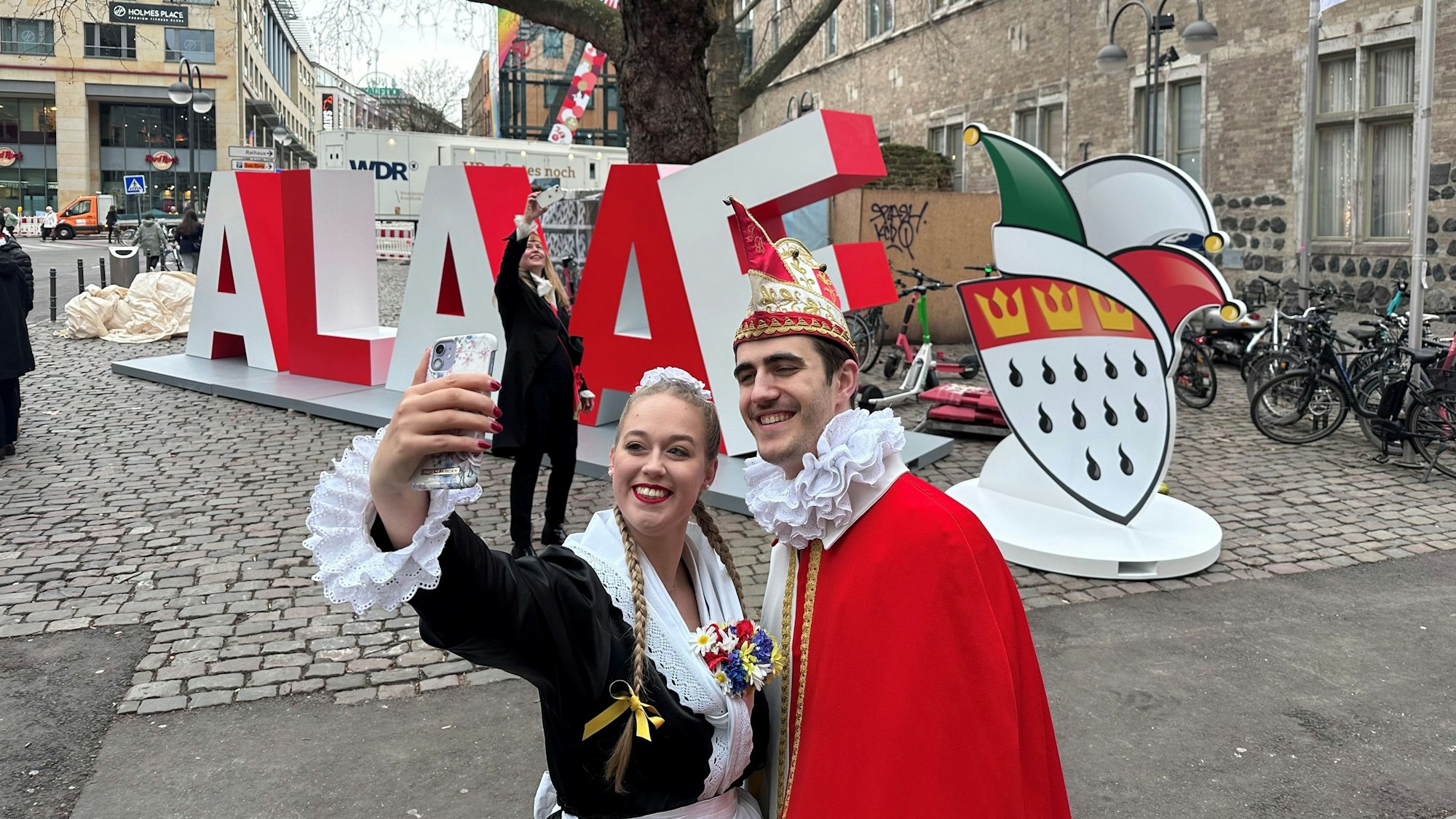 05.01.2023, Köln: Vor dem Gürzenich hat das Festkomitee Kölner Karneval einen Alaaf-Schriftzug aus Metall aufgestellt. Der soll während des Jubiläumsjahres als mobiles "Denkmal" durch die Stadt wandern und den Menschen ein Motiv für Selfies und Fotos bieten. Im Vordergrund Aline Schäfer und Jannik Soerries von den Lyskircher Hellige Knäächte un Mägde. Foto: Stefan Worring