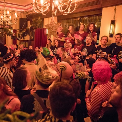 Menschen in Karnevalskostümen stehen dicht gedrängt in einer Kneipe.