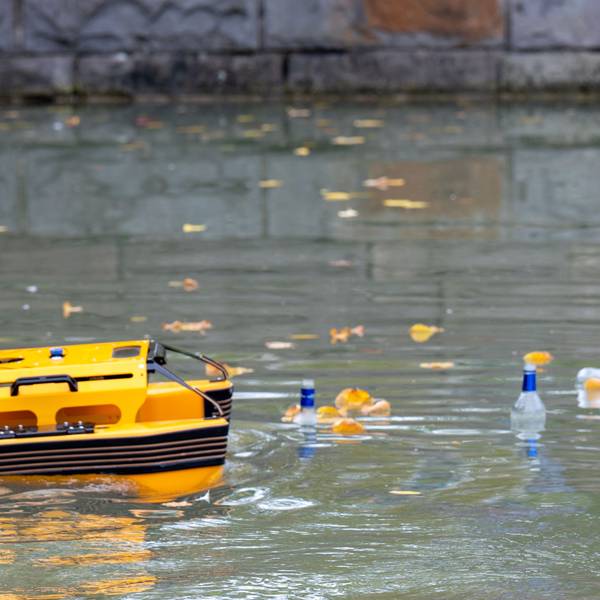 Das orange Boot auf dem Aachener Weiher. Rechts schwimmen Flaschen.