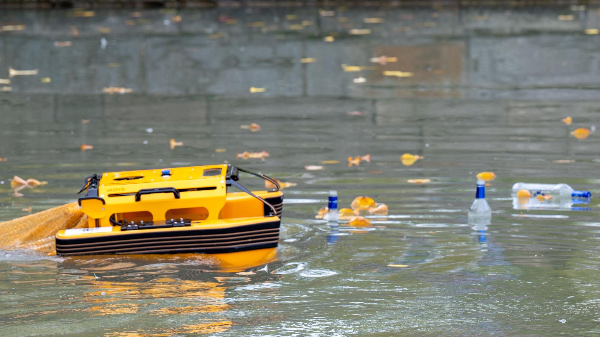 Das orange Boot auf dem Aachener Weiher. Rechts schwimmen Flaschen.