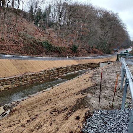 Der Murbach ist an der Brücke der Kreisstraße im Tal bei Dohm mit einer massiven Natursteinmauer befestigt worden.