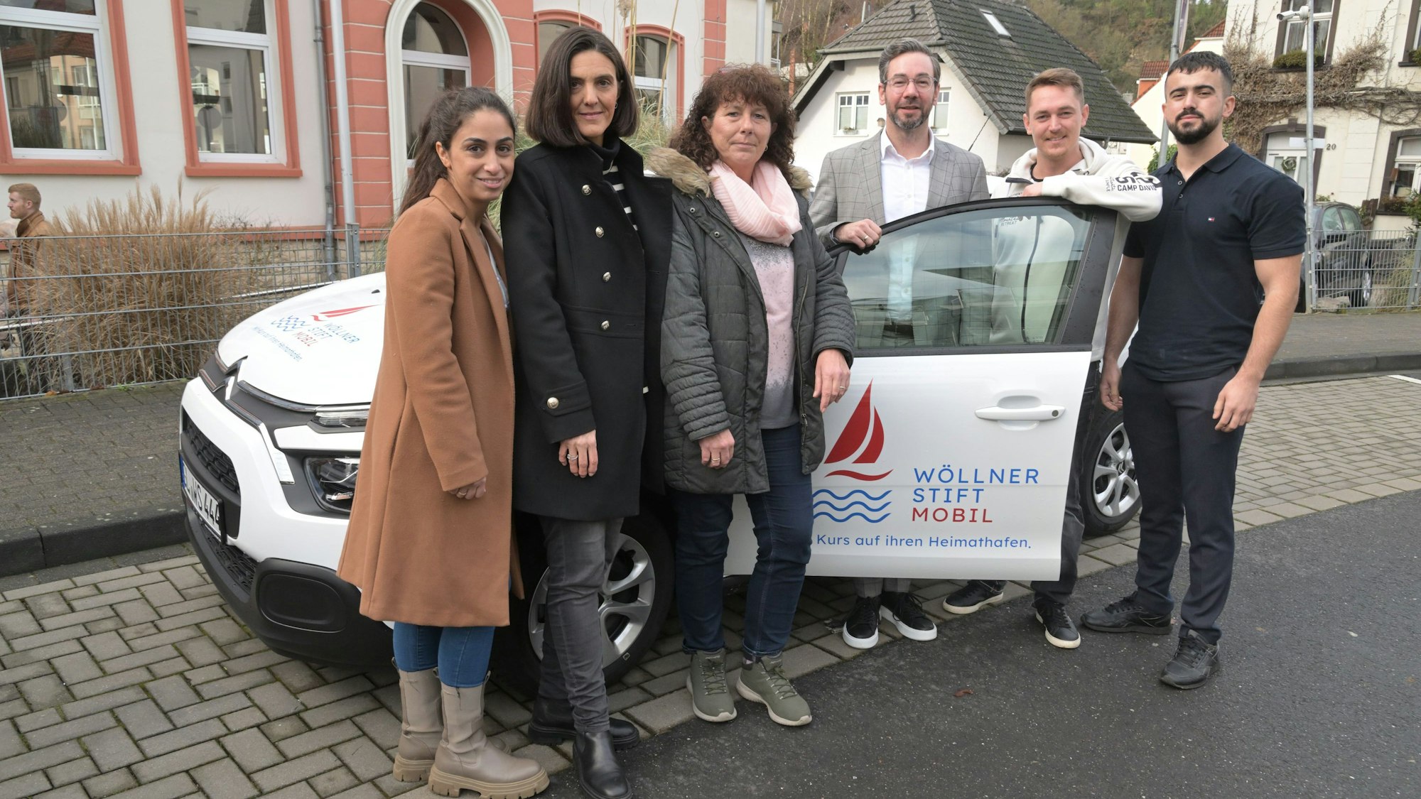 Das Team des Wöllner-Stifts steht in Rösrath-Hoffnungsthal vor dem weißen Wöllner-Stift-Mobil.