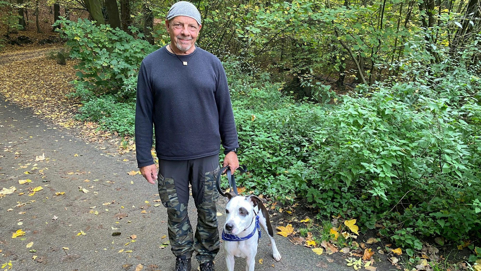 Michael Simon steht mit einem Hund an der Leine auf einem Waldweg.