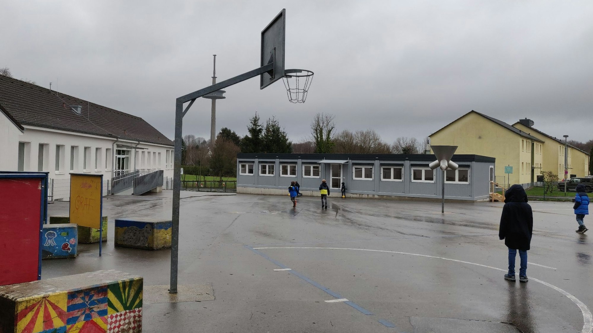 Auf dem Pausenhof der Grundschule Witzhelden steht neben der Turnhalle ein grauer Fertigbau mit zwei neuen Klassenzimmern.