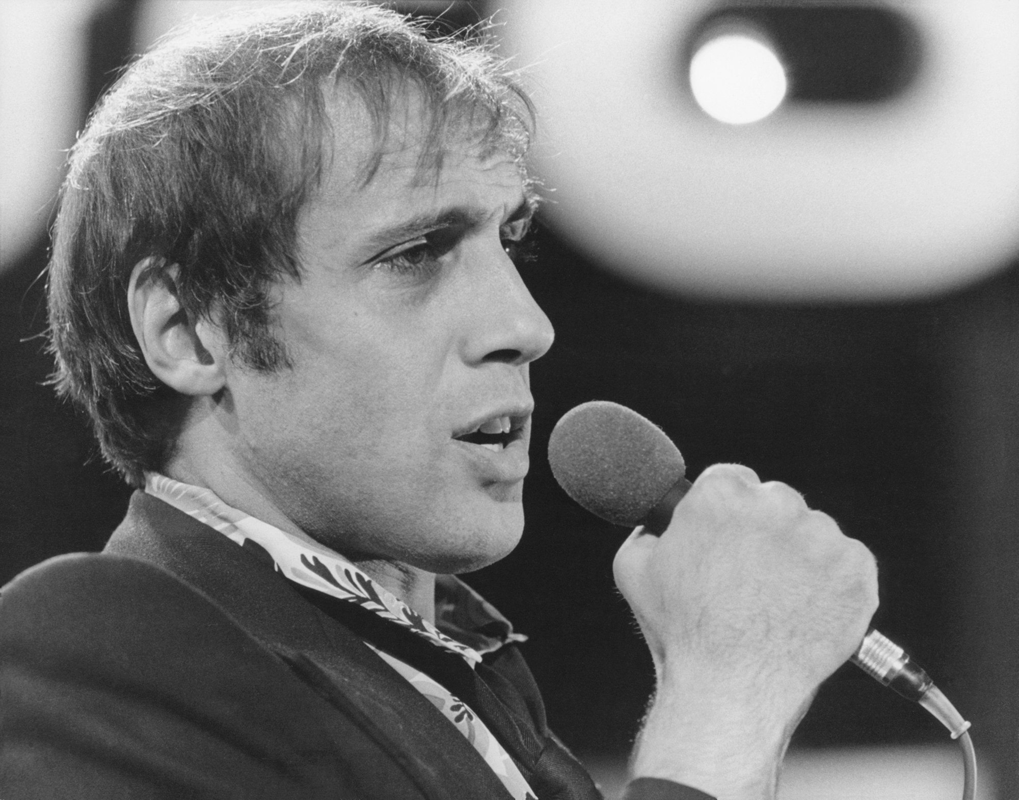 Ein schwarz-weiß Foto von Celentano, er singt in ein Mikrofon.
