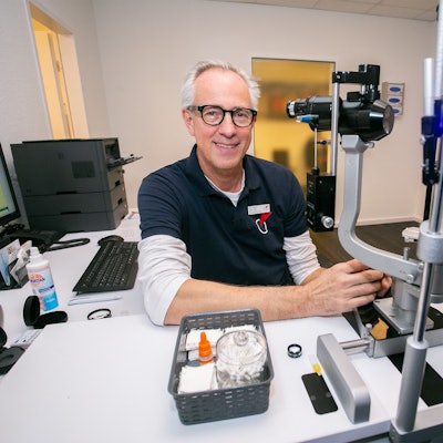 Augenarzt Dr. Ludger Henke sitzt vor einem Augenmessgerät für Patienten.
