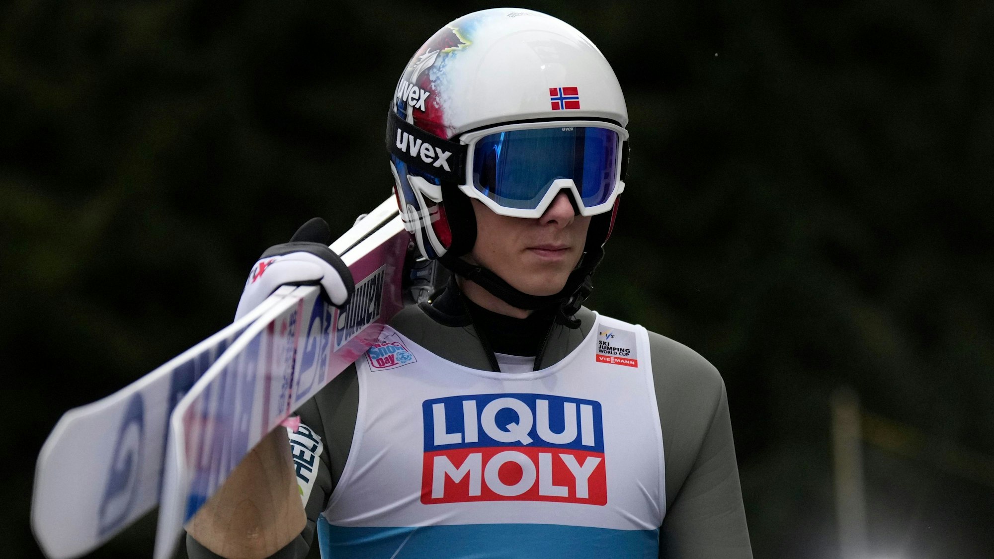 Halvor Egner Granerud hat seine Skier geschultert und geht in Bischofshofen in Richtung Springerturm.