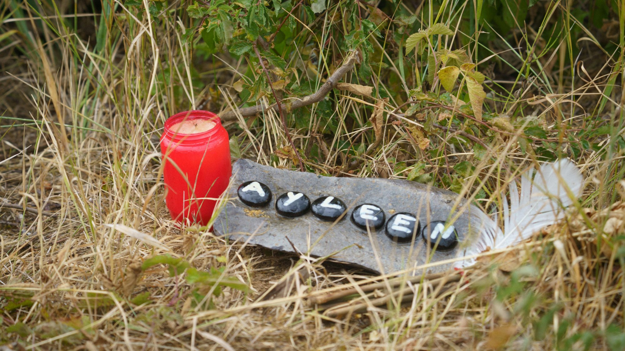 Eine Kerze und eine Tafel mit dem Namen Ayleen liegt am Ufer des Teufelsee im hessischen Wetteraukreis, in dem die Leiche der 14-jährigen Ayleen gefunden wurde.