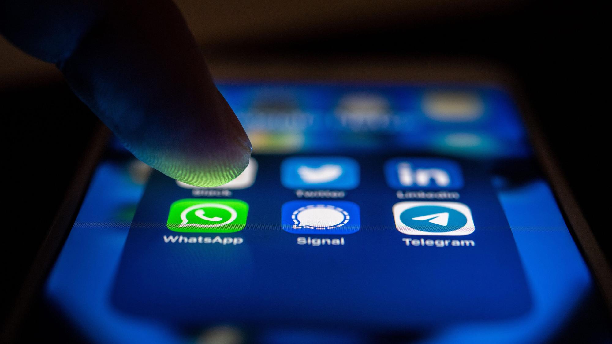 Ein Finger berührt das Display eines Smartphones, um einen Messangerdienst zu aktivieren.