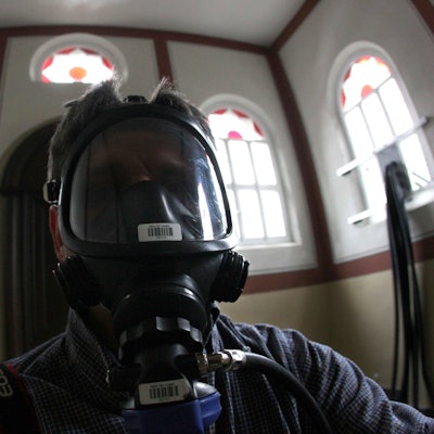 Ein Besucher mit einer umluftunabhängigen Schutzmaske steht während der Kunstaktion 245 Kubikmeter Autoabgase in der Synagoge in Stommeln.