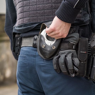 Der Rücken eines Bundespolizisten, der gerade nach hinten in seinen Gürtel greift, um Handschellen hervor zu holen.