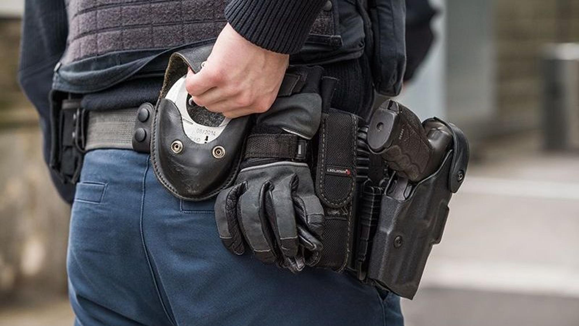 Ein Beamter der Bundespolizei greift zu seinen Handschellen hinten an der Hosentasche.