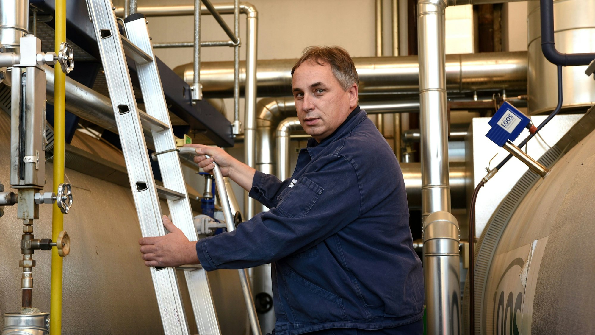 Wolfgang Stier klettert eine Leiter in der Fabrik hoch.