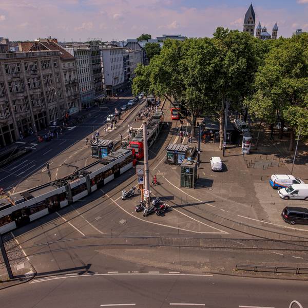 Ansicht des Neumarkt in Köln von oben: Es sind Bahnschienen, Straßenbahnen und eine Kreuzung zu sehen.
