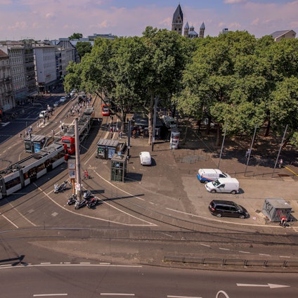 Ansicht des Neumarkt in Köln von oben: Es sind Bahnschienen, Straßenbahnen und eine Kreuzung zu sehen.