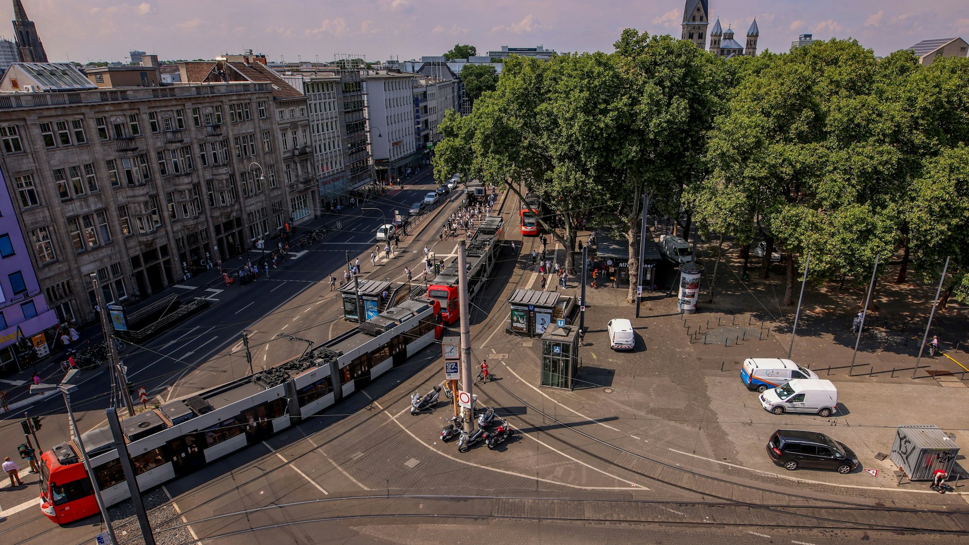 Die Luftaufnahme zeigt einen Teil des Neumarkts und der Cäcilienstraße. Eine Straßenbahn fährt Richtung Heumarkt.