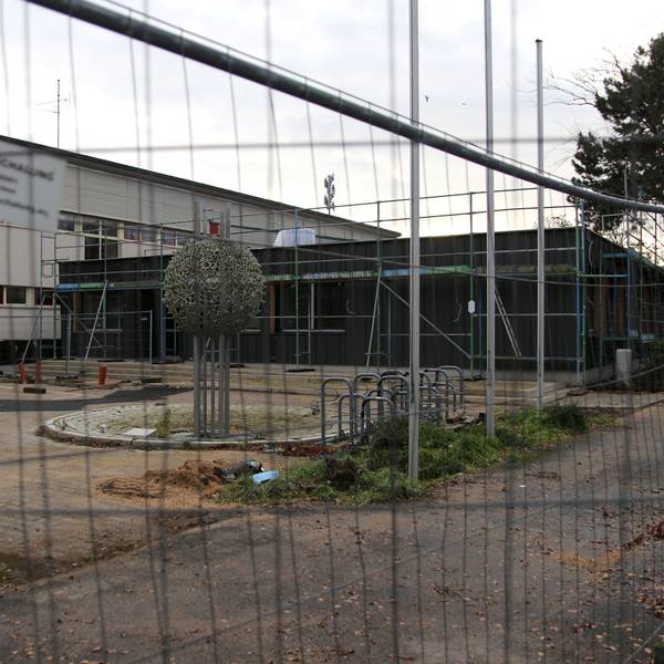 Die Horionschule in Pulheim, fotografiert durch einen Bauzaun hindurch fotografiert