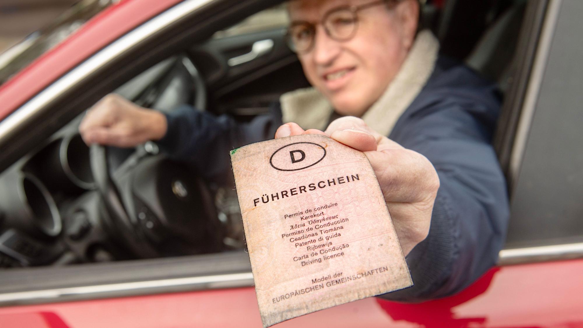Ein älterer Autofahrer zeigt bei der Führerscheinkontrolle einen alten, rosa Papierführerschein vor.