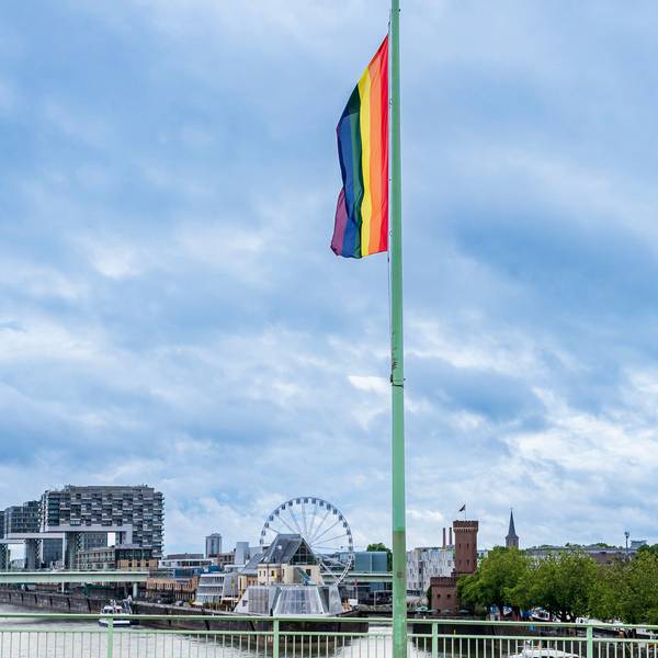 Auf der Deutzer Brücke hängt eine Regenbogenflagge. Im Hintergrund die Kranhäuser und ein Riesenrad. Das Bild stammt aus dem Pride Month im Juni 2022.